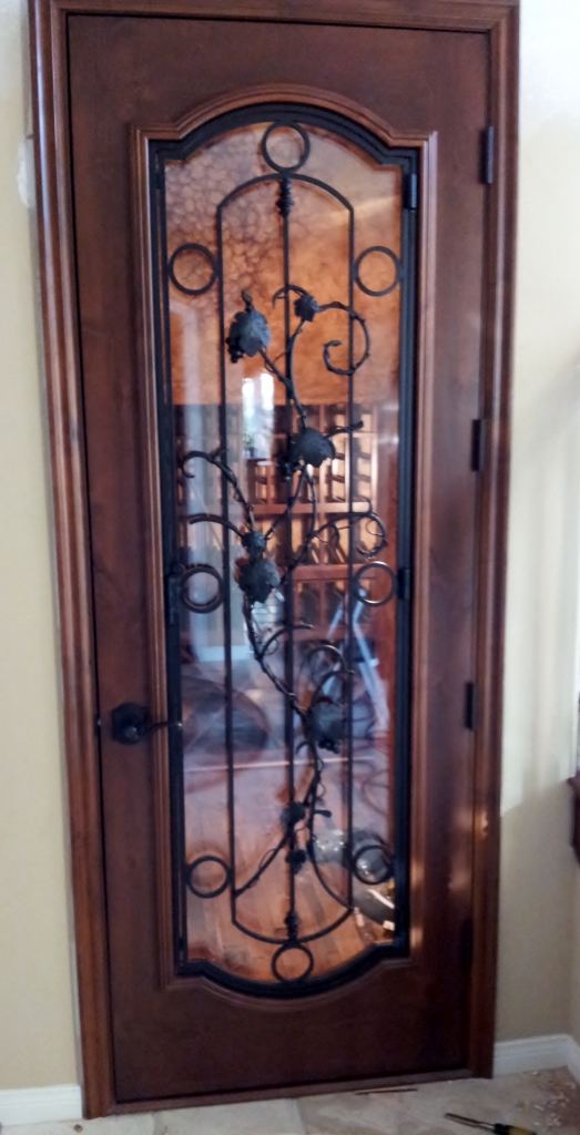 Seville - knotty Alder prefit wine cellar door with operable wrought iron detail