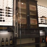 This truly impressive cigar humidor and wine cellar is enclosed by clear, frameless glass walls and door.