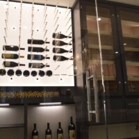 A clear glass door with a stainless steel handle is a beautiful and modern way to welcome people into your custom wine cellar.