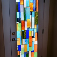 The stained glass Barolo door lets in a bit of outside light into this residential wine cellar in a beautiful and unique way.