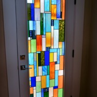 The stained glass Barolo door lets in a bit of outside light into this residential wine cellar in a beautiful and unique way.