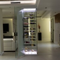 This modern glass wine cellar features bottles suspended on cables and enclosed in glass.