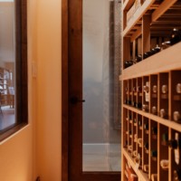 This traditional home wine cellar is enclosed by a wooden door with a large central glass panel.