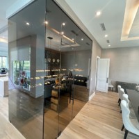 Smoky glass is a wonderful choice for the walls and door of this home wine cellar.