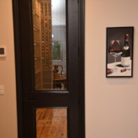 From the outside, you can see a vast portion of the custom wine racks because of the tempered glass door. View of Custom Wine Racks Through A Glass Door